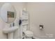 Updated half-bathroom includes pedestal sink, built-in shelving, and wood-look floors at 715 Saddlebred Ln, Locust, NC 28097