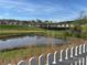 A community pond view with a white picket fence in the foreground, showcasing neighborhood homes at 715 Saddlebred Ln, Locust, NC 28097