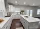 Bright kitchen featuring white cabinets, a large island, and dark wood flooring at 8011 Caliterra Dr, Charlotte, NC 28227