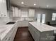Bright kitchen featuring white cabinets, a large island, and dark wood flooring at 8011 Caliterra Dr, Charlotte, NC 28227
