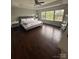 Main bedroom featuring dark wood floors, three windows, a tray ceiling, and a ceiling fan at 8011 Caliterra Dr, Charlotte, NC 28227