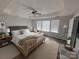 Comfortable main bedroom suite featuring tray ceilings, three windows, dark wood floors, and a ceiling fan at 8011 Caliterra Dr, Charlotte, NC 28227