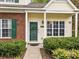 Close-up of charming townhome with brick and siding, green door and shutters, and manicured front yard at 8230 Rudolph Rd, Charlotte, NC 28216