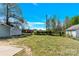A spacious backyard with lush green grass, mature trees, and storage sheds at 109 Broad St, Shelby, NC 28152