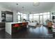 Open-concept living room with dark wood floors, modern kitchen island, and bright natural light from the large windows at 1100 Metropolitan Ave # 314, Charlotte, NC 28204