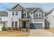 Charming two-story home with a gray garage, stone accents, manicured lawn, and inviting front door at 11036 Shreveport Dr, Huntersville, NC 28078