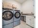 Modern laundry room boasts side-by-side washer and dryer units, complemented by ample storage and a utility sink at 11036 Shreveport Dr, Huntersville, NC 28078