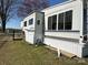 This mobile home features white siding, mountain graphics, and sits on a well-maintained grassy lot at 134 Putt Putt Ln, New London, NC 28127