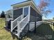Charming home exterior featuring a screened porch, staircase, and gated yard with partial view of the travel trailer at 134 Putt Putt Ln, New London, NC 28127