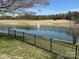 Scenic lake view with fountain feature, bordered by lush greenery and a black metal fence, offering a peaceful setting at 134 Putt Putt Ln, New London, NC 28127
