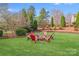 Lush backyard featuring a cozy fire pit area surrounded by mature trees and manicured landscaping at 1504 Ridge Haven Rd, Waxhaw, NC 28173