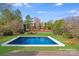 Backyard oasis featuring a sparkling pool and an inviting firepit area, surrounded by lush greenery and mature trees at 1504 Ridge Haven Rd, Waxhaw, NC 28173