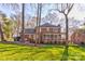 Backyard view of brick home, including screened porch, overlooking lush greenery and mature trees at 1537 Wheaton Nw Way, Concord, NC 28027