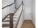 View of the staircase with dark wood handrail and balusters with wood floors and white door at 19751 Feriba Pl, Cornelius, NC 28031