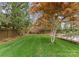 A well-manicured backyard featuring a lush lawn, mature trees, and a brick wall providing privacy at 2015 Pellyn Wood Dr, Charlotte, NC 28226