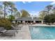 A luxurious backyard with a pool, lounge chairs, and outdoor dining with lush landscaping and mature trees at 2015 Pellyn Wood Dr, Charlotte, NC 28226