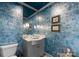 Stylish powder room showcasing blue textured walls, decorative mirror, sconces, and a gray vanity at 2015 Pellyn Wood Dr, Charlotte, NC 28226