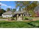 Beautiful front exterior of home with lush lawn, a vine covered pergola, seating, and mature trees at 2015 Pellyn Wood Dr, Charlotte, NC 28226
