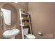 Stylish half-bathroom featuring a round mirror, a small sink, and decorative wall shelves at 2035 Palace Way, Indian Land, SC 29707