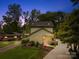 Inviting two-story home at twilight featuring a cozy front porch and lush landscaping at 21220 Rio Oro Dr, Cornelius, NC 28031