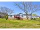 View of home exterior with lawn, mature trees, deck, and blue sky background at 216 Sylvan Rd, China Grove, NC 28023