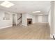 Spacious basement features a cozy brick fireplace, staircase, and light wood laminate flooring at 2714 Dogwood Cir, Charlotte, NC 28208