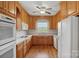Well-lit kitchen with oak cabinets, white appliances, and a view of the yard at 2805 Sadler Rd, Alexis, NC 28006