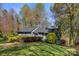 Charming single-story home with gray siding, dark shutters, surrounded by colorful landscaping and mature trees at 3846 22Nd Ne St, Hickory, NC 28601