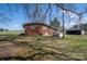 Back view of brick home featuring a large yard with mature trees and an outbuilding at 396 Tower Rd, Vale, NC 28168