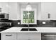 Close-up of kitchen sink with modern fixtures and black tile backsplash by window at 4522 Woods End Ln, Charlotte, NC 28277