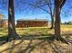 Back of house surrounded by trees, a large yard, and a glimpse of a clear blue sky at 614 Normandy Rd, Lancaster, SC 29720