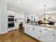 Open kitchen and living area with stainless appliances, white cabinets, and hardwood floors at 6325 Hawkwood Ln, Charlotte, NC 28277
