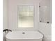 Bright bathroom featuring a luxurious soaking tub beneath a frosted window for privacy at 6614 Old Providence Rd, Charlotte, NC 28226