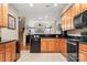 Open kitchen featuring wood cabinets and stainless steel appliances, flowing into a living area at 744 Ledgestone Ct, Tega Cay, SC 29708