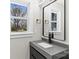 Updated bathroom featuring a sleek gray vanity, black fixtures, and a window view at 7816 Wallace Ln, Charlotte, NC 28212