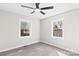 A modern bedroom with gray laminate flooring, white walls, and a black ceiling fan at 7816 Wallace Ln, Charlotte, NC 28212