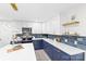 Modern kitchen features white upper cabinets and blue lower cabinets with quartz counters and stainless steel appliances at 7816 Wallace Ln, Charlotte, NC 28212