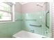 Well-lit bathroom featuring a bathtub, tiled walls, and safety handrails at 783 Carpenter Ave, Mooresville, NC 28115