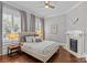 Cozy bedroom with a decorative fireplace, hardwood floors, large windows, and soft, neutral colors at 806 Sunnyside Ave, Charlotte, NC 28204