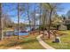 Scenic backyard with a lush lawn, a brick pathway, mature trees, and waterfront access with docks and boat slips at 8194 Mallard Rd, Denver, NC 28037