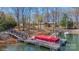 Lakeside property with a private dock, covered boat lift, and a scenic view of the serene, wooded shoreline at 8194 Mallard Rd, Denver, NC 28037