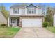 Inviting home features a 2-car garage, stone details, neutral siding and a neatly manicured lawn at 9230 Avery Meadows Dr, Charlotte, NC 28216