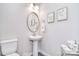 Cozy half bath with pedestal sink, round mirror, and decorative artwork on the gray walls at 9413 Liberty Hill Dr, Mint Hill, NC 28227