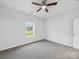 A cozy bedroom with a ceiling fan and a bright window, showing neutral carpet and walls at 1067 Old Charlotte Rd, Concord, NC 28027