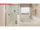 Bright bathroom featuring a glass enclosed shower, soaking tub, and a large window overlooking a wooded lot at 124 Fordingbridge Ln, Mooresville, NC 28115