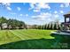 Large, lush green backyard with a fire pit and manicured lawn, perfect for outdoor enjoyment at 1311 Sunnys Halo Ln, Waxhaw, NC 28173