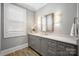 Well-lit powder room features quartz counters, custom cabinets and window with blinds at 1311 Sunnys Halo Ln, Waxhaw, NC 28173