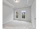 Primary bedroom with a tray ceiling and two large windows allowing for ample natural light at 212 Gilead Rd, Huntersville, NC 28078