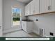 Bright laundry room with patterned floors, sink, white cabinets, and large window view at 280 Gilead Rd, Huntersville, NC 28078