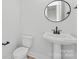 Modern powder room featuring a pedestal sink, round mirror, and sleek fixtures at 3437 Byrnes St, Charlotte, NC 28205